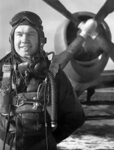 Clyde Knisley posing in flying gear with plane